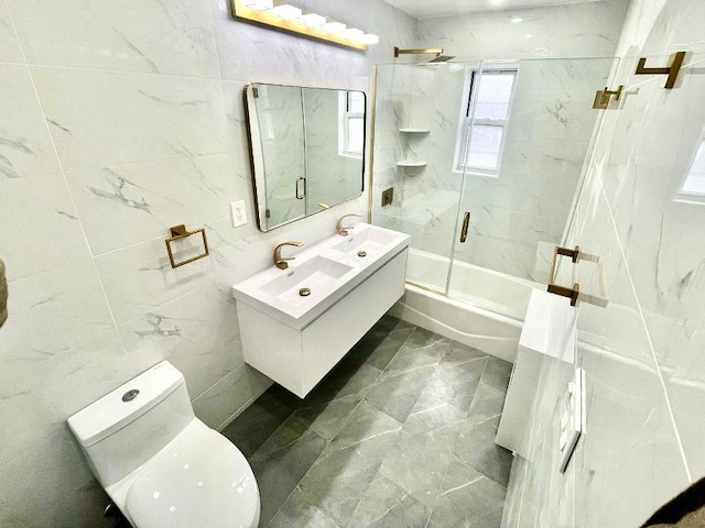 full bathroom featuring tile walls, shower / bath combination with glass door, vanity, and toilet