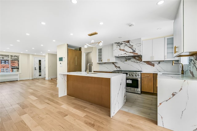 kitchen featuring white cabinetry, sink, premium appliances, and a kitchen island with sink