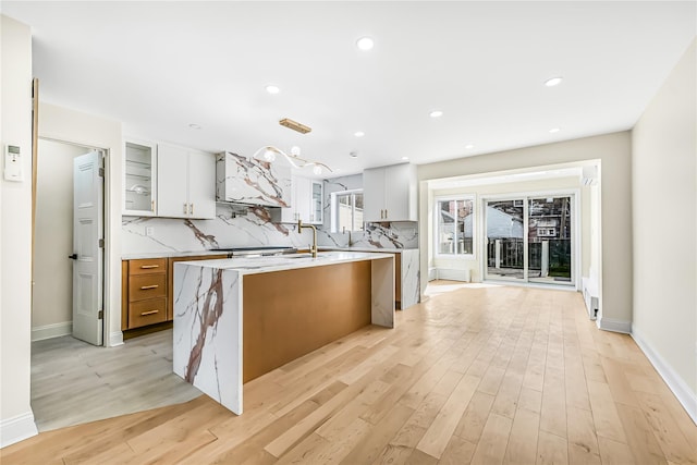 kitchen with tasteful backsplash, a center island, white cabinetry, and light hardwood / wood-style flooring