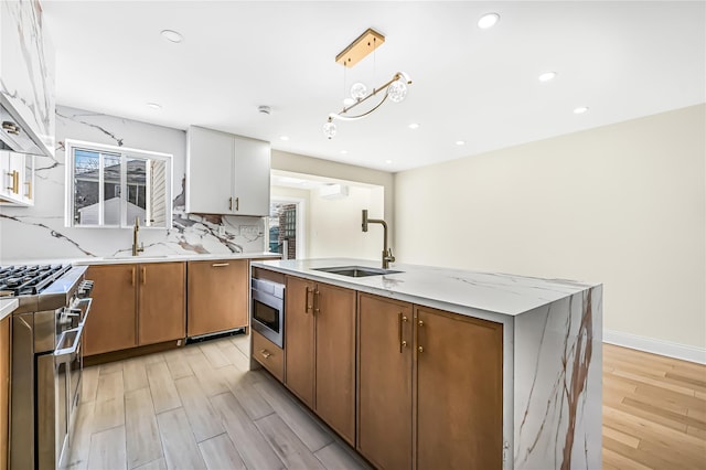 kitchen featuring white cabinets, appliances with stainless steel finishes, a kitchen island, sink, and light wood-type flooring