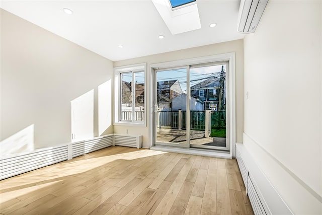 interior space featuring light wood-type flooring, a skylight, and a wall unit AC