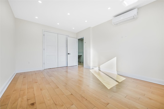 unfurnished room featuring light wood-type flooring and a wall mounted air conditioner