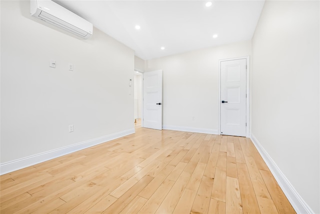 unfurnished room featuring light hardwood / wood-style floors and a wall unit AC