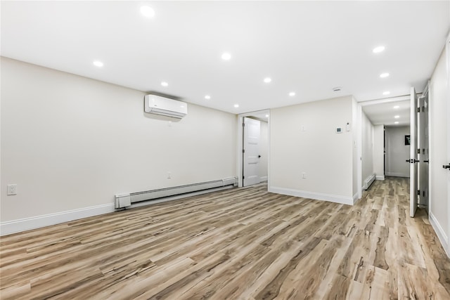 basement with a baseboard heating unit, light hardwood / wood-style flooring, and an AC wall unit