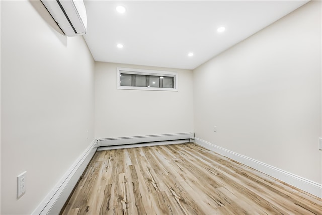 spare room featuring baseboard heating, light hardwood / wood-style flooring, and a wall unit AC