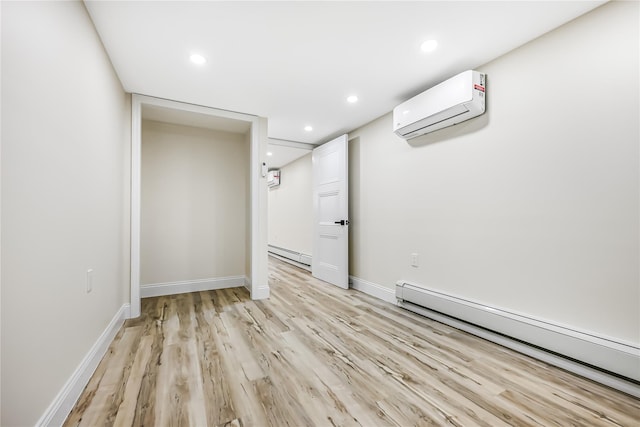 interior space with a baseboard heating unit, a wall mounted AC, and light hardwood / wood-style flooring