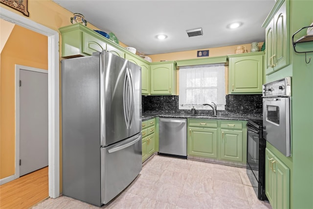 kitchen with sink, green cabinetry, dark stone countertops, tasteful backsplash, and appliances with stainless steel finishes