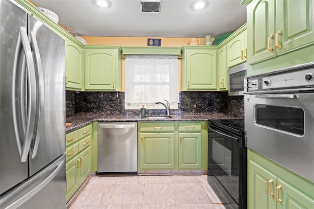 kitchen featuring stainless steel appliances, green cabinetry, dark stone counters, light tile patterned flooring, and sink