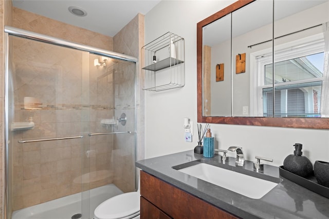 bathroom featuring vanity, a shower with shower door, and toilet