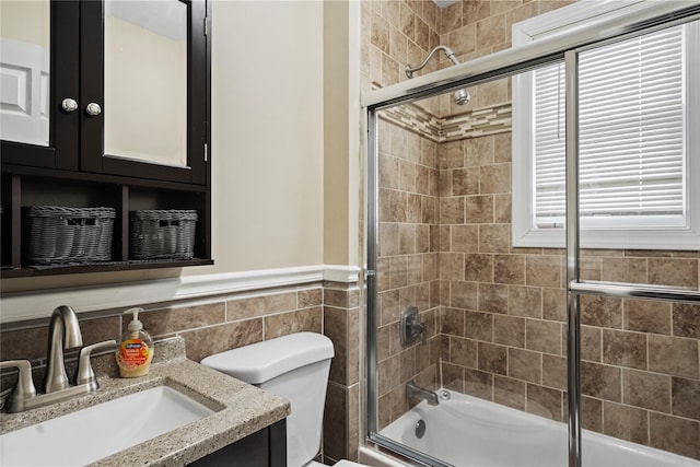 full bathroom featuring vanity, toilet, shower / bath combination with glass door, and tile walls