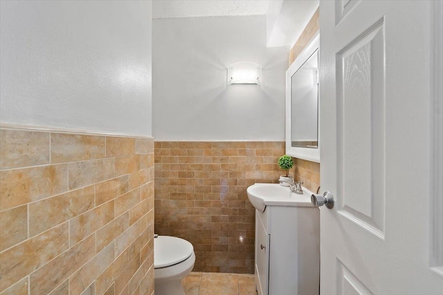 bathroom featuring tile walls, vanity, tile patterned floors, and toilet