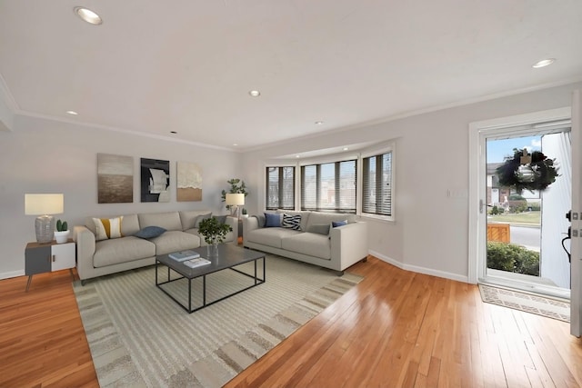 living room featuring light wood-type flooring, ornamental molding, and a healthy amount of sunlight