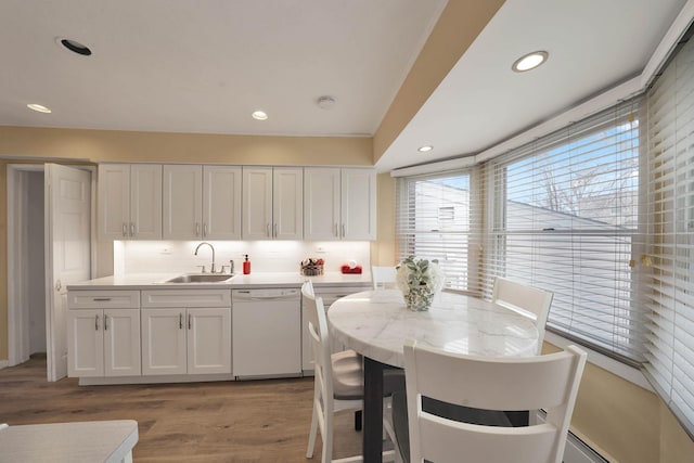 kitchen with white cabinetry, backsplash, dishwasher, light hardwood / wood-style flooring, and sink