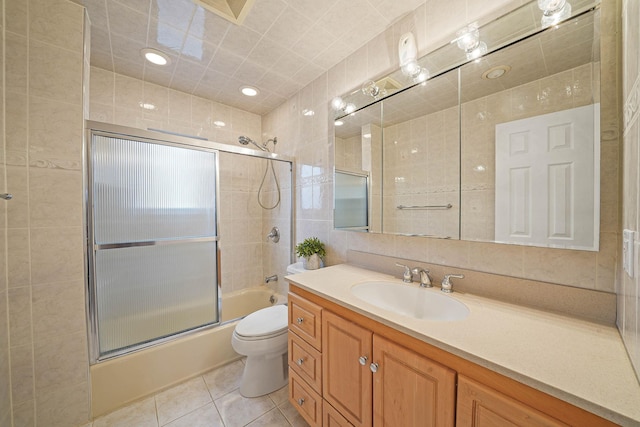 full bathroom featuring toilet, combined bath / shower with glass door, tile walls, tile patterned floors, and vanity