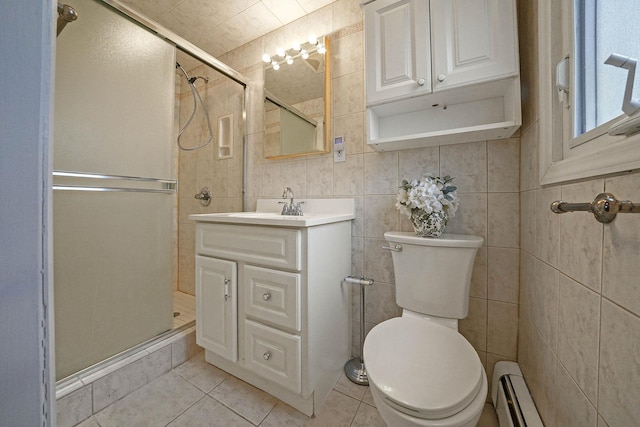 bathroom featuring baseboard heating, tile patterned flooring, a shower with door, vanity, and tile walls