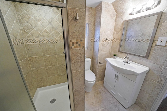 bathroom with toilet, tile patterned flooring, tile walls, an enclosed shower, and vanity