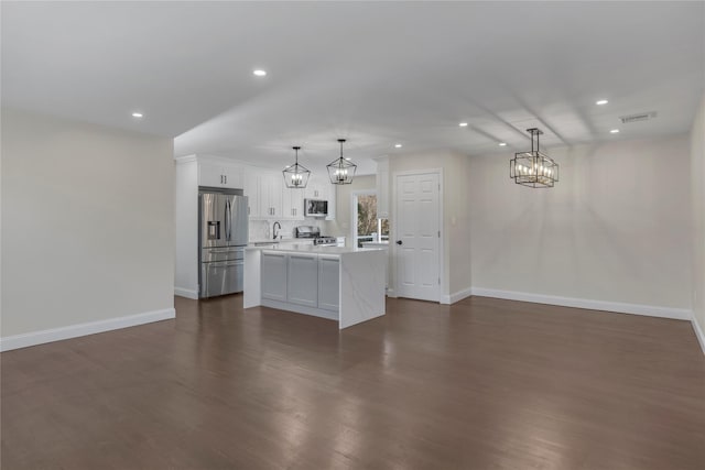 kitchen featuring pendant lighting, white cabinets, a center island, appliances with stainless steel finishes, and dark hardwood / wood-style floors