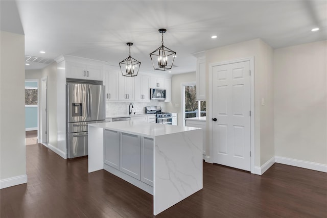 kitchen with a center island, hanging light fixtures, appliances with stainless steel finishes, plenty of natural light, and white cabinets