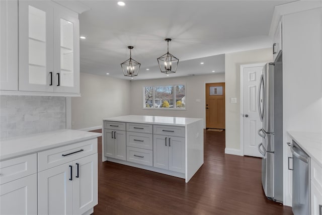 kitchen with backsplash, pendant lighting, white cabinets, and stainless steel appliances