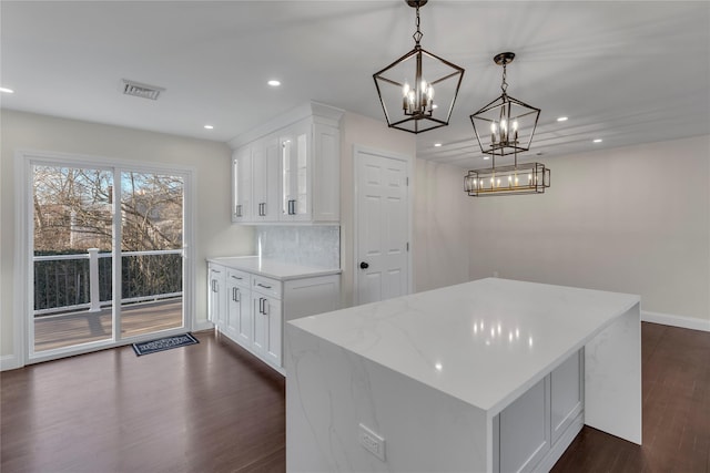 kitchen with white cabinetry, decorative backsplash, dark wood-type flooring, hanging light fixtures, and light stone counters