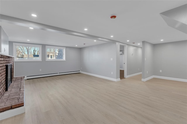 unfurnished living room featuring light wood-type flooring, a fireplace, and a baseboard radiator