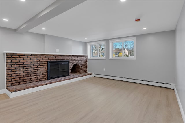 unfurnished living room featuring a baseboard heating unit, a brick fireplace, and light hardwood / wood-style flooring