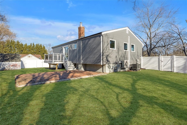 rear view of property featuring central AC and a lawn