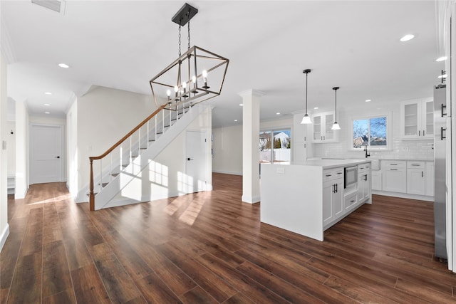 kitchen with a kitchen island, appliances with stainless steel finishes, white cabinetry, backsplash, and hanging light fixtures