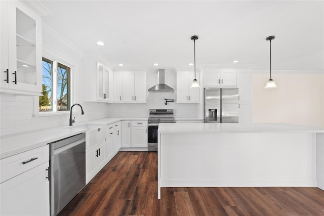 kitchen featuring appliances with stainless steel finishes, pendant lighting, white cabinetry, sink, and wall chimney exhaust hood