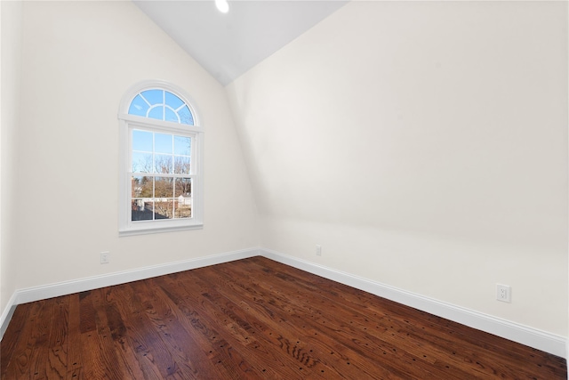 empty room featuring vaulted ceiling and dark wood-type flooring