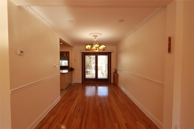 doorway to outside featuring a notable chandelier, crown molding, and hardwood / wood-style floors