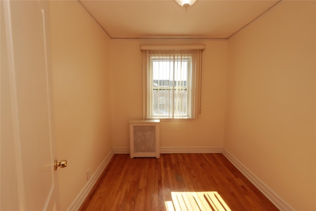 unfurnished room featuring hardwood / wood-style floors and radiator heating unit