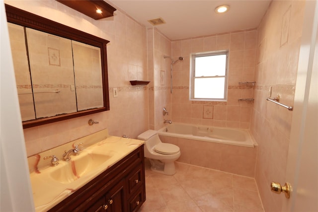 full bathroom featuring tile patterned flooring, toilet, tile walls, tiled shower / bath, and vanity