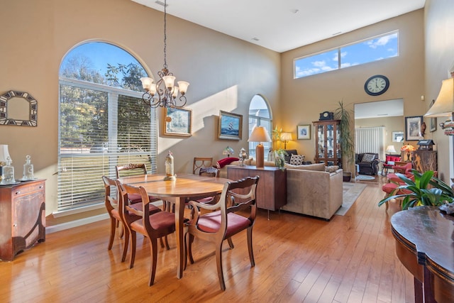 dining space with a notable chandelier, a high ceiling, and light wood-type flooring