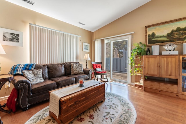 living room with light hardwood / wood-style floors and vaulted ceiling