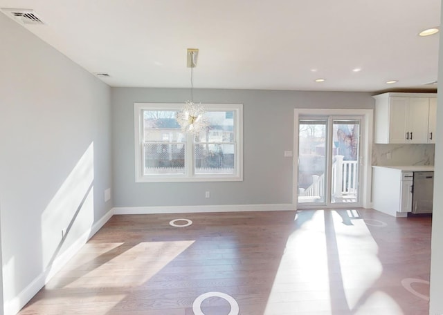 unfurnished dining area featuring an inviting chandelier and dark hardwood / wood-style floors