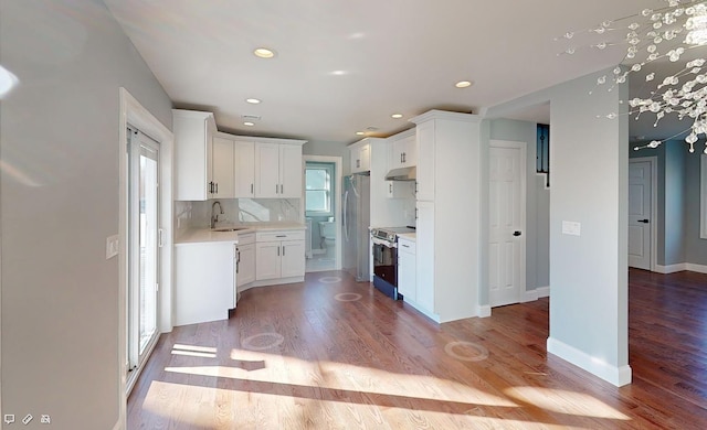 kitchen with stainless steel appliances, white cabinetry, light wood-type flooring, and backsplash