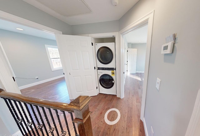 laundry area featuring stacked washer / drying machine and hardwood / wood-style flooring