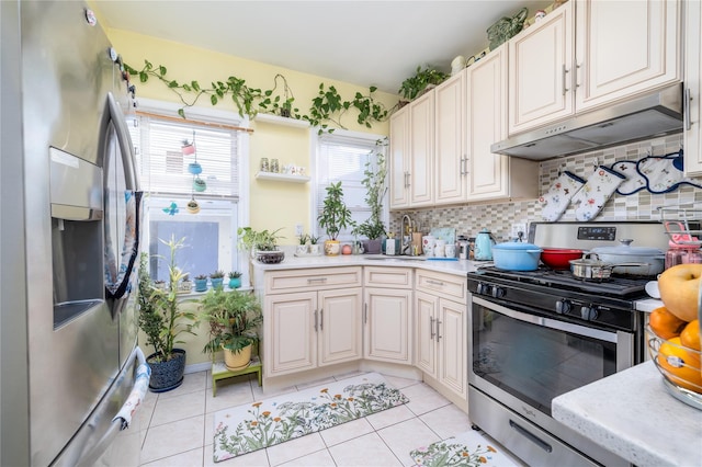 kitchen with sink, light tile patterned floors, appliances with stainless steel finishes, and tasteful backsplash