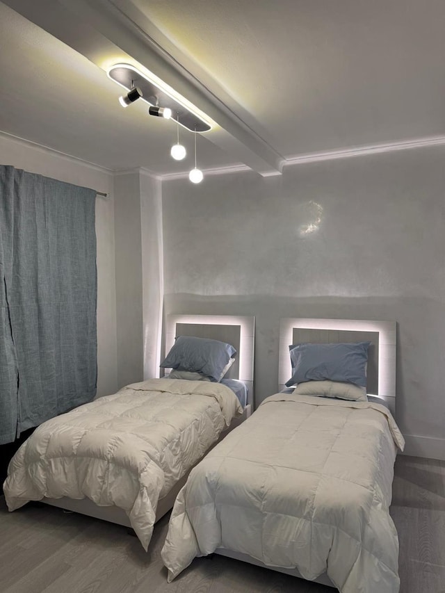 bedroom featuring beamed ceiling and wood-type flooring