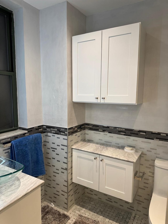 bathroom with tile patterned floors, vanity, toilet, and tile walls