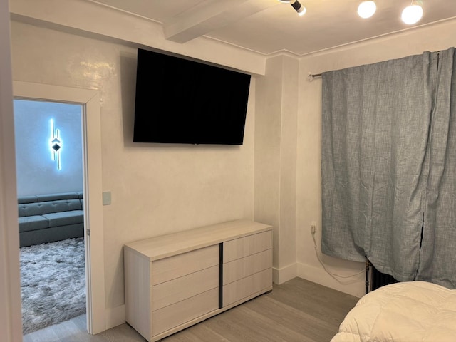 bedroom with beamed ceiling and light hardwood / wood-style floors