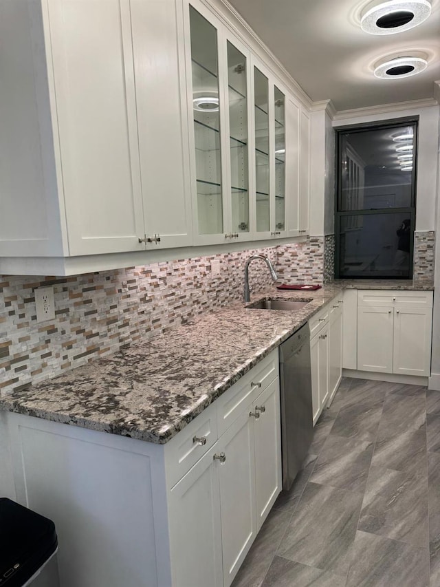 kitchen with decorative backsplash, stainless steel dishwasher, light stone counters, sink, and white cabinets