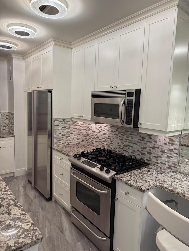 kitchen featuring light stone counters, white cabinetry, stainless steel appliances, and tasteful backsplash