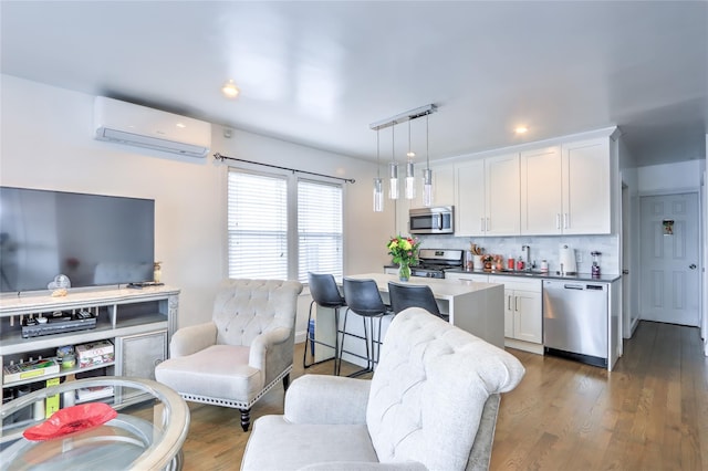 kitchen featuring stainless steel appliances, a wall unit AC, pendant lighting, and white cabinetry