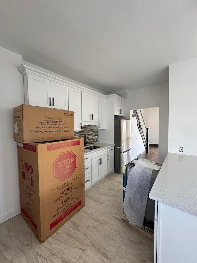 kitchen with white cabinetry, backsplash, and freestanding refrigerator