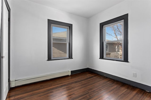 empty room featuring a baseboard heating unit, a wealth of natural light, baseboards, and dark wood-style floors