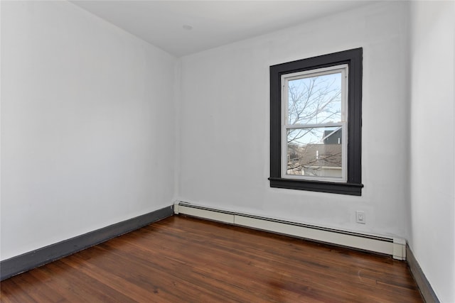 unfurnished room with a baseboard heating unit, dark wood finished floors, and baseboards