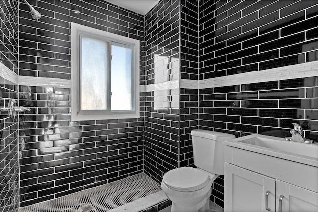 full bath featuring toilet, tiled shower, tile walls, and vanity