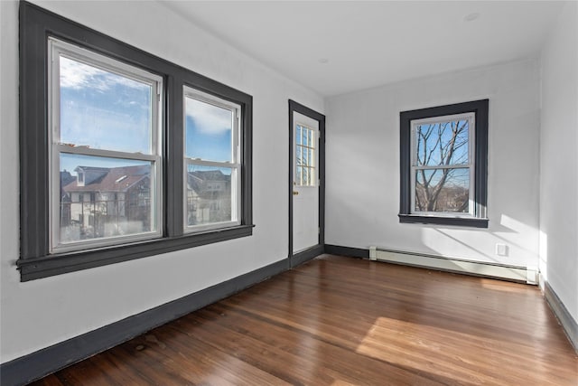 empty room with dark wood-style floors, baseboards, and a baseboard heating unit